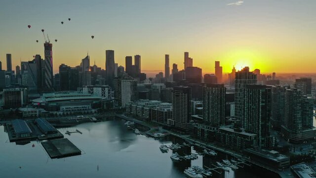 Aerial hyperlapse of Melbourne city at sunrise, with hot air balloon flying over