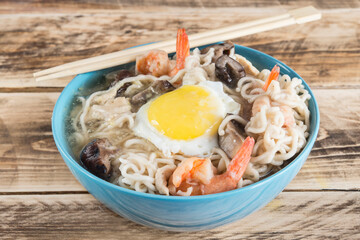 Chinese soup with udon noodles, pork, boiled eggs, mushrooms and prawns close-up in a bowl on the...