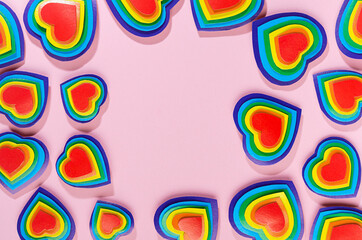 Lgbt Valentines day background - rainbow hearts as abstract frame on pastel pink backdrop, top view.