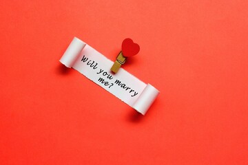 Will you marry me label on torn paper with red paper background