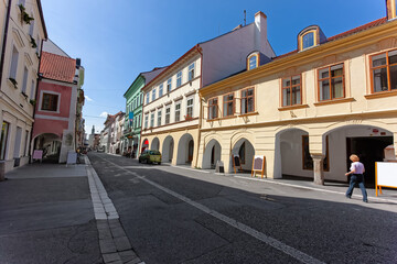 traditional European buildings and a tower with a copper dome and a clock on a sunny day in Jicin, Czech Republic.