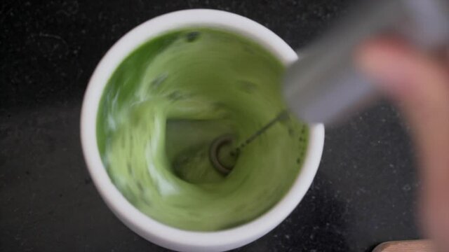 Using whisk to prepare matcha latte