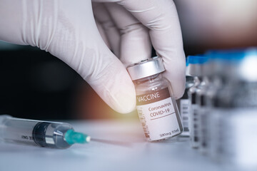 Hand wearing a medical nitrile surgical glove and pick or hold a bottle of covid19 vaccine. Vaccination, immunization, treatment to cure Covid 19 Corona Virus infection Concept