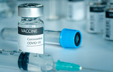 Covid-19 vaccine and syringe injection on a laboratory bench. to fight the coronavirus sars-cov-2 pandemic. Medicine infectious concept.