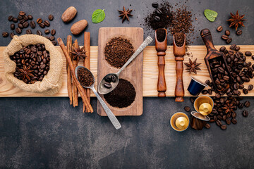  Roasted coffee beans with coffee powder and flavourful ingredients for make tasty coffee setup on dark stone background.