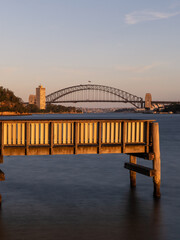 Pier and Sydney Harbour Bridge under the golden light.