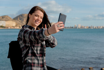 Wonderful cheerful young woman with blue eyes happily poses in the open air, makes a self portrait...