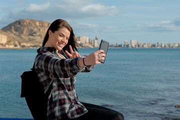 Wonderful cheerful young woman with blue eyes happily poses in the open air, makes a self portrait...