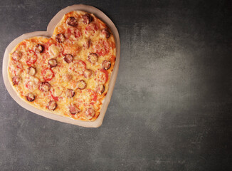 Delicious pizza in the form of a heart for valentine's day on dark table background