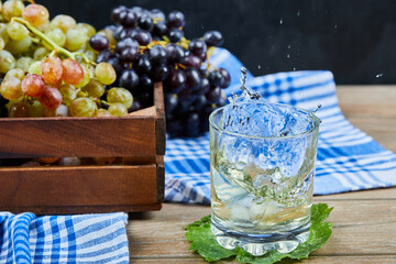 Bunch of grapes in a wooden basket and a glass of wine on wooden table