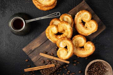 Puff. Flaky sugar Palmiers cookies on a wooden serving board on a black kitchen table. Sweet homemade cakes	