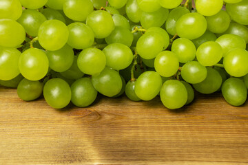 Green grapes on wooden table, close up.