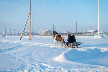 Rural landscape with horse and people on sleigh. A harnessed horse carrying locals from the village shop on a sunny day. - 408238776