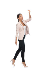 smart casual brunette woman in pink jacket making a hand calling gesture