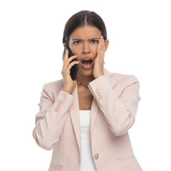 shocked young businesswoman opening mouth and talking on the phone