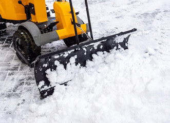 Schnee schieben mit einem Traktor auf dem Fußweg