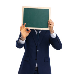 young elegant businessman hiding behind empty blackboard