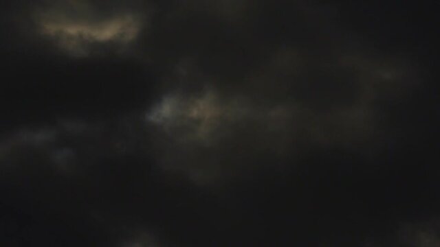 Sun behind dark dramatic storm clouds moving fast from right to left in real time