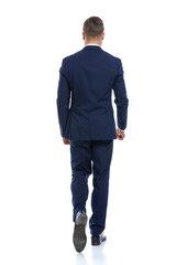 elegant young man in navy blue suit walking