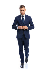 confident young model walking and unbuttoning navy blue suit