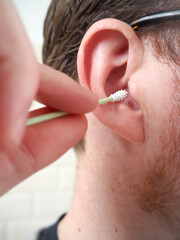 Man cleaning his ear with a reusable silicone q-tip
