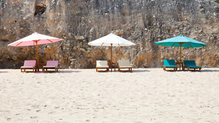 Beach for tourists. Sun loungers and umbrellas on the white sand. Bali island resort, Indonesia.