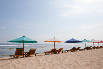 Fototapeta premium Beach for tourists. Sun loungers and umbrellas on the white sand. Bali island resort, Indonesia.