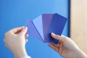 In hands of palette with blue shades against blue wall