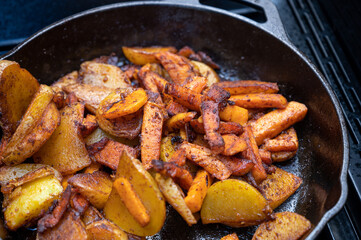 süßkartoffel und kartoffel schnitten in einer gusseisernen pfanne aus dem grill