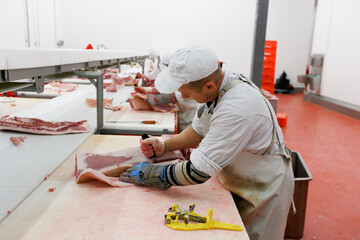 A group of worker in meat factory, chopped a fresh beef meat in pieces on work table, industry food.