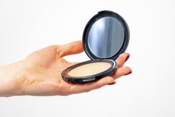 Female hand holding compact powder against gray background