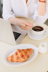 Hands of a woman with coffee and laptop in a summer outdoor cafe