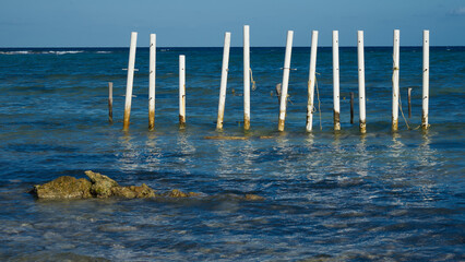 White poles driven into the blue sea water in Bacalar, Mexico