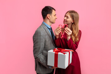 romantic couple, an elegant man in a suit and an attractive young woman in a red dress with a gift...