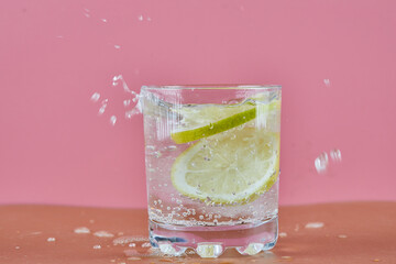 A glass of cold refreshing lemonade on pink background