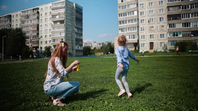 Mother and child blowing soap bubbles outdoor.