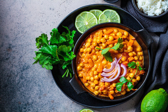 Vegan Chickpea Curry With Rice And Cilantro In Black Plate, Dark Background. Indian Cuisine Concept.