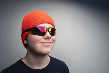 Handsome little boy teenager in a sports red hat and sports glasses smiling on a white background