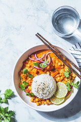 Vegan chickpea curry with rice and cilantro in white bowl, white marble background. Indian cuisine...