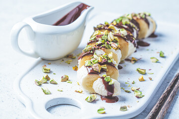 Sweet banana sushi with chocolate and nuts, white background. Vegan dessert concept.
