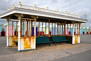 Rusty derelict seafront shelter with Brighton beach huts, Sussex, UK