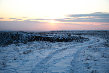 Snowy road in winter at sunset