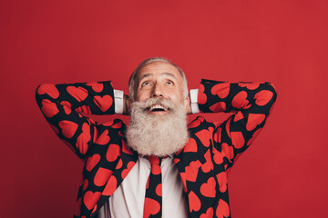 Photo of excited old man hands behind head look up empty space wear heart print tux isolated red...
