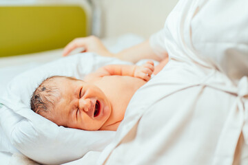 Fototapeta na wymiar Newborm baby screaming just after born. Newborn baby boy in maternity hospital.