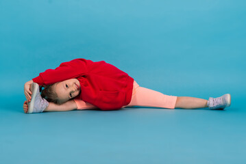 Beautiful girl sits on a splits isolated on a blue background