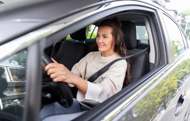 Fototapeta na wymiar safety and people concept - happy smiling young woman or female driver driving car in city