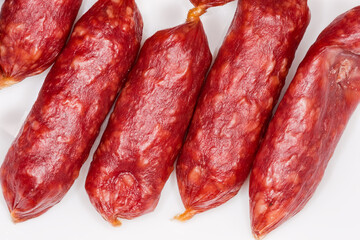 Small thin dry cured sausages on white surface, close-up