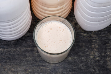 Obraz na płótnie Canvas Glass of fermented milk drink against plastic bottles, top view