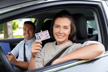 driver courses, exam and people concept - young woman with license and driving school instructor...