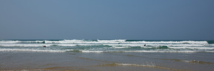 Cornwall people having fun in the waves and sea in wetsuits with surf boards at Porthtowan Cornish north coast